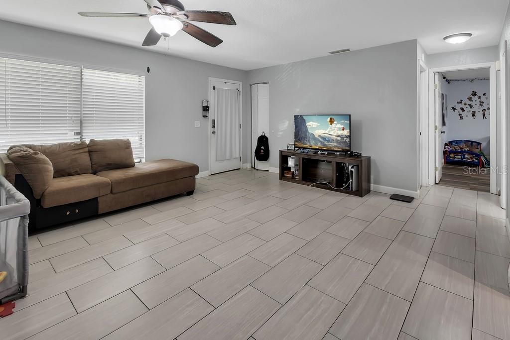 A living room features light gray tile flooring, a brown sectional sofa, and a television — 2222 6TH AVENUE, DELAND, FL