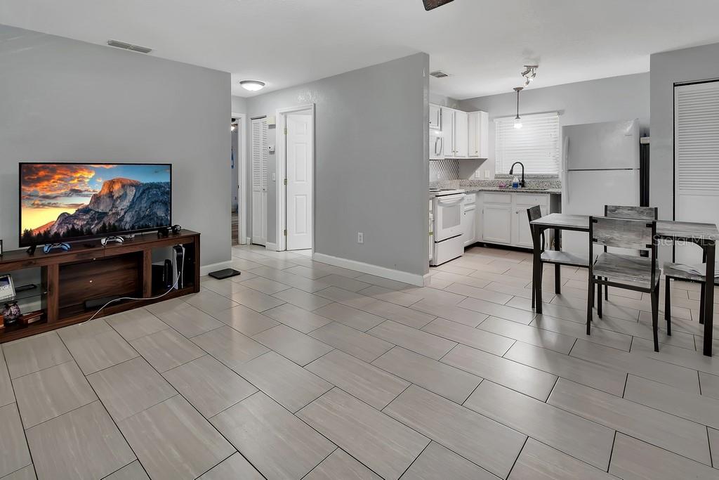 A living room with light tile flooring opens into a kitchen with white cabinets — 2222 6TH AVENUE, DELAND, FL