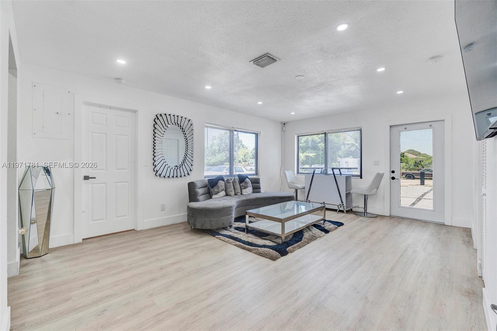 A living room features light wood flooring, a curved gray sofa, and a glass table — 4029 SW 22nd St, West Park FL 33023, WEST PARK, FL