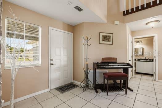 An entryway with tile flooring, a white front door, a coat rack, and an electronic keyboard — 1617 MAPLESTEAD COURT, ORLANDO, FL