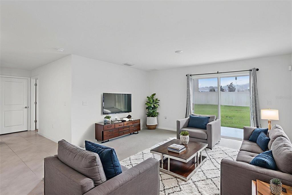 A living room features gray furniture, a wooden media console, and a sliding glass door — 7530 BROAD POINTE DRIVE, ZEPHYRHILLS, FL