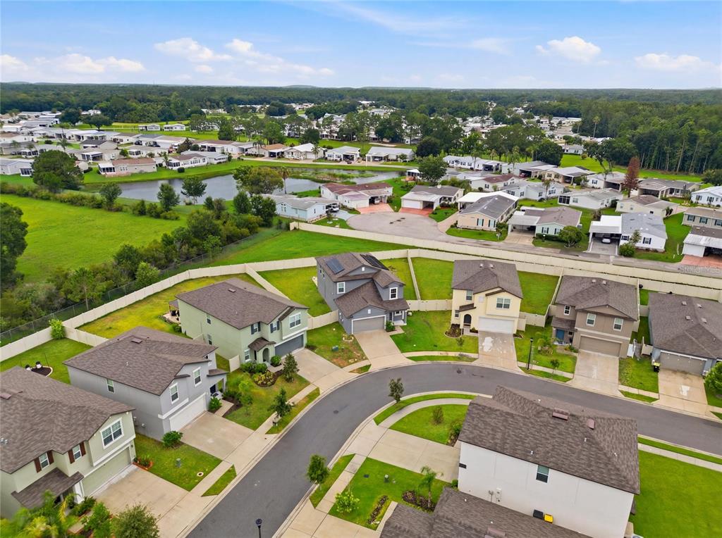 An aerial view shows a suburban neighborhood with houses, a pond, and green spaces — 1779 YELLOW TRAIL, LAKELAND, FL
