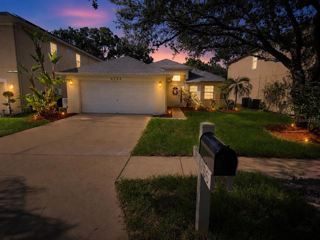 The exterior view shows a house entrance with a walkway, stucco walls, and bay windows — 4756 WHISPERING WIND AVENUE, TAMPA, FL