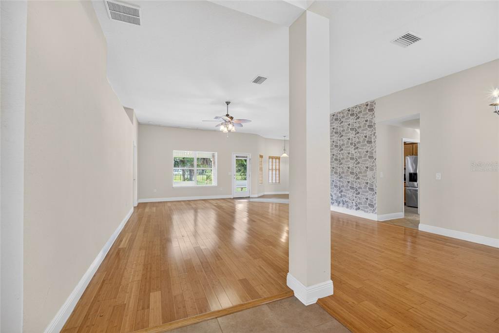 An open-concept living area features light wood flooring, a stone accent wall, and a ceiling fan — 4319 SW 63RD STREET, OCALA, FL