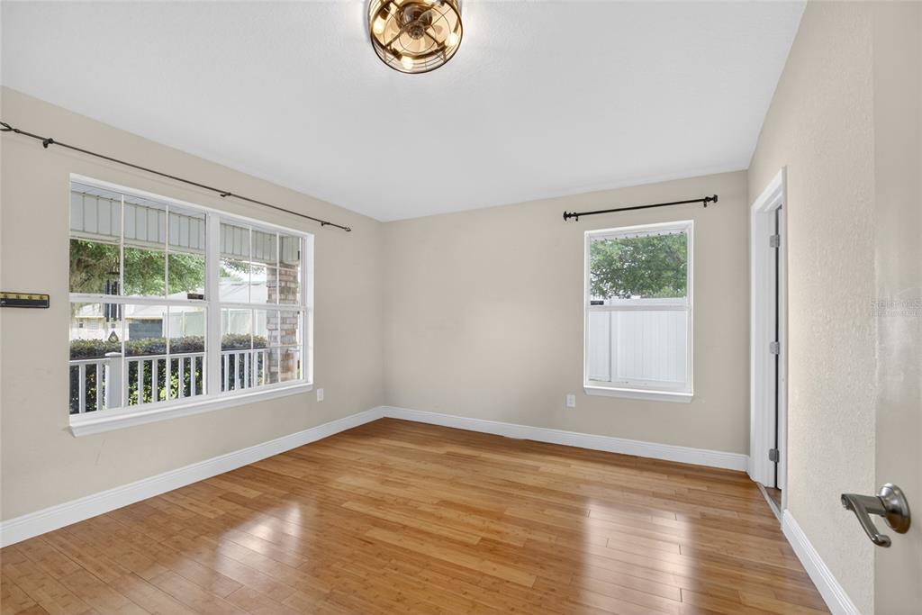 An empty room with light-colored walls, hardwood flooring, two windows, and a ceiling light fixture — 4319 SW 63RD STREET, OCALA, FL