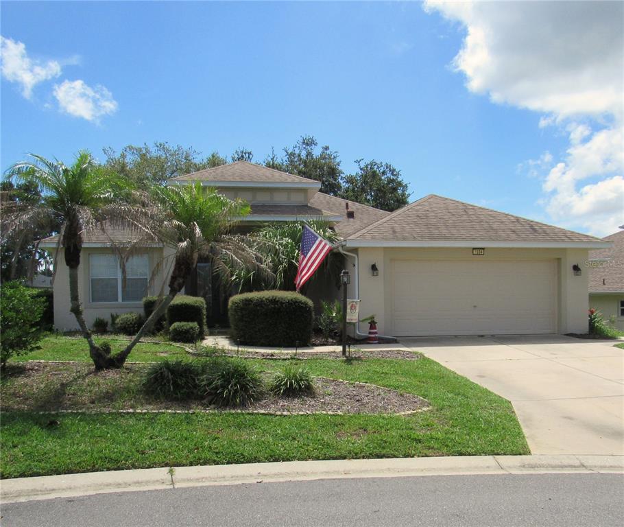 A single-story house with a beige exterior, a two-car garage, and a front yard — 3204 ANTIGUA BAY LANE, TAVARES, FL