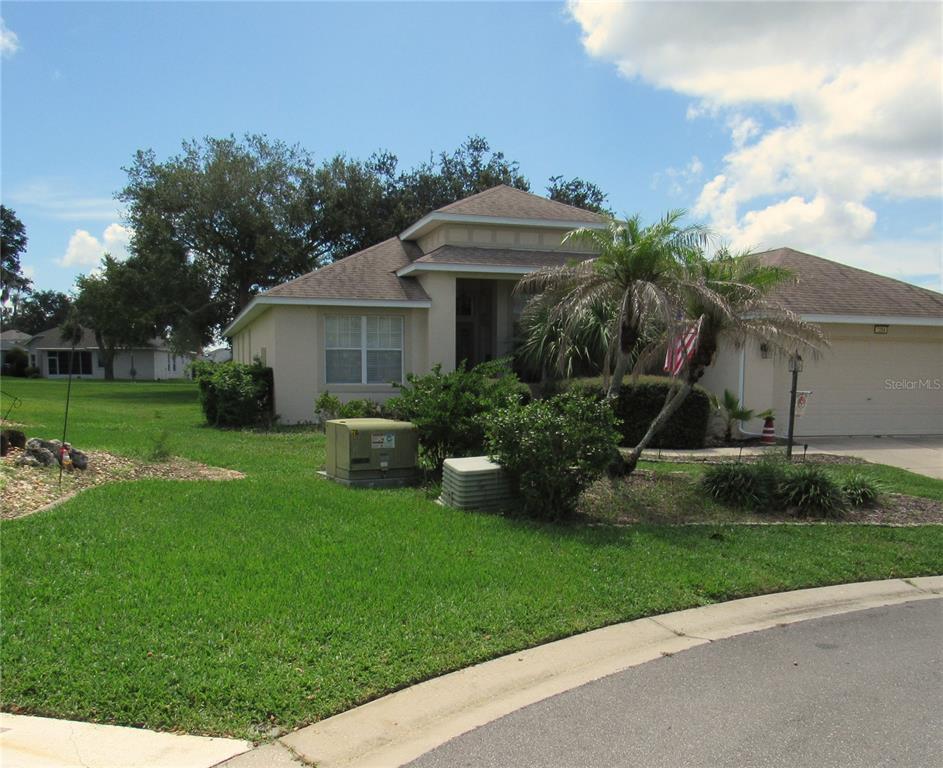 A single-story suburban house with a tan stucco exterior and a palm tree in front — 3204 ANTIGUA BAY LANE, TAVARES, FL