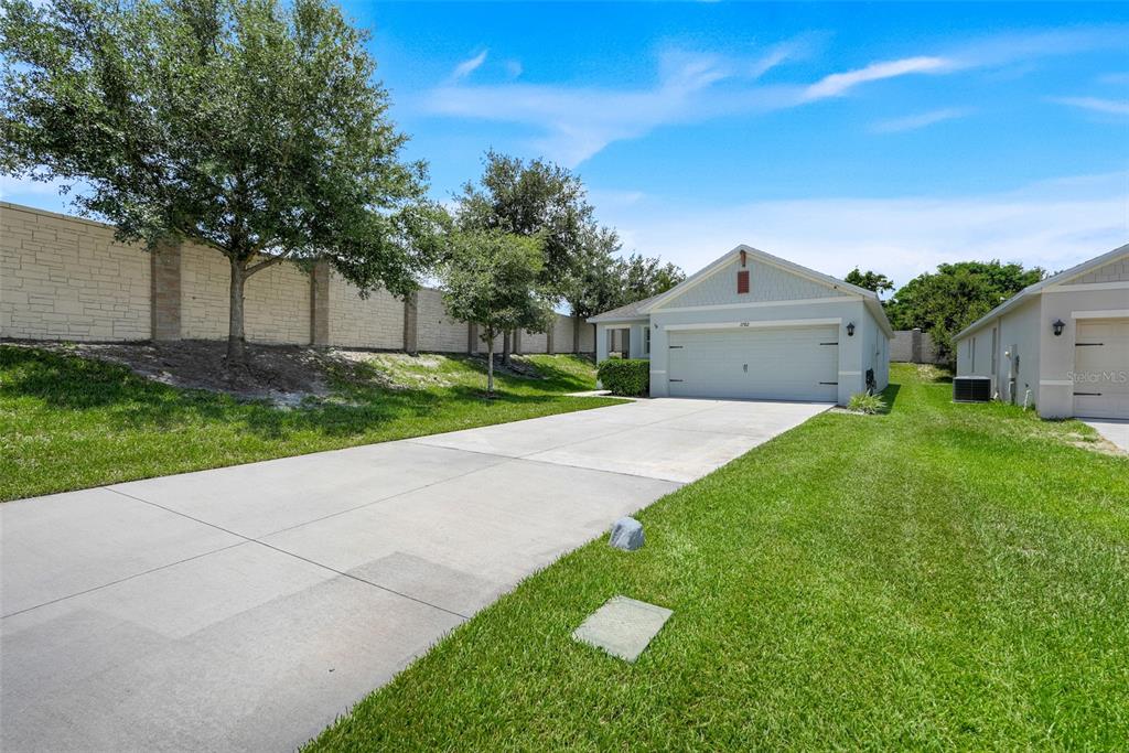A single-story house with a concrete driveway and a large stone wall in the background — 2782 TIMBER HAWK CIRCLE, OCOEE, FL