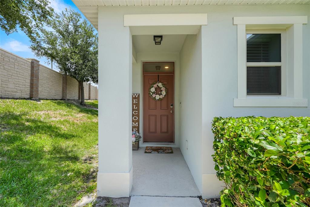The exterior view shows a covered entryway with a brown front door and a welcome sign — 2782 TIMBER HAWK CIRCLE, OCOEE, FL