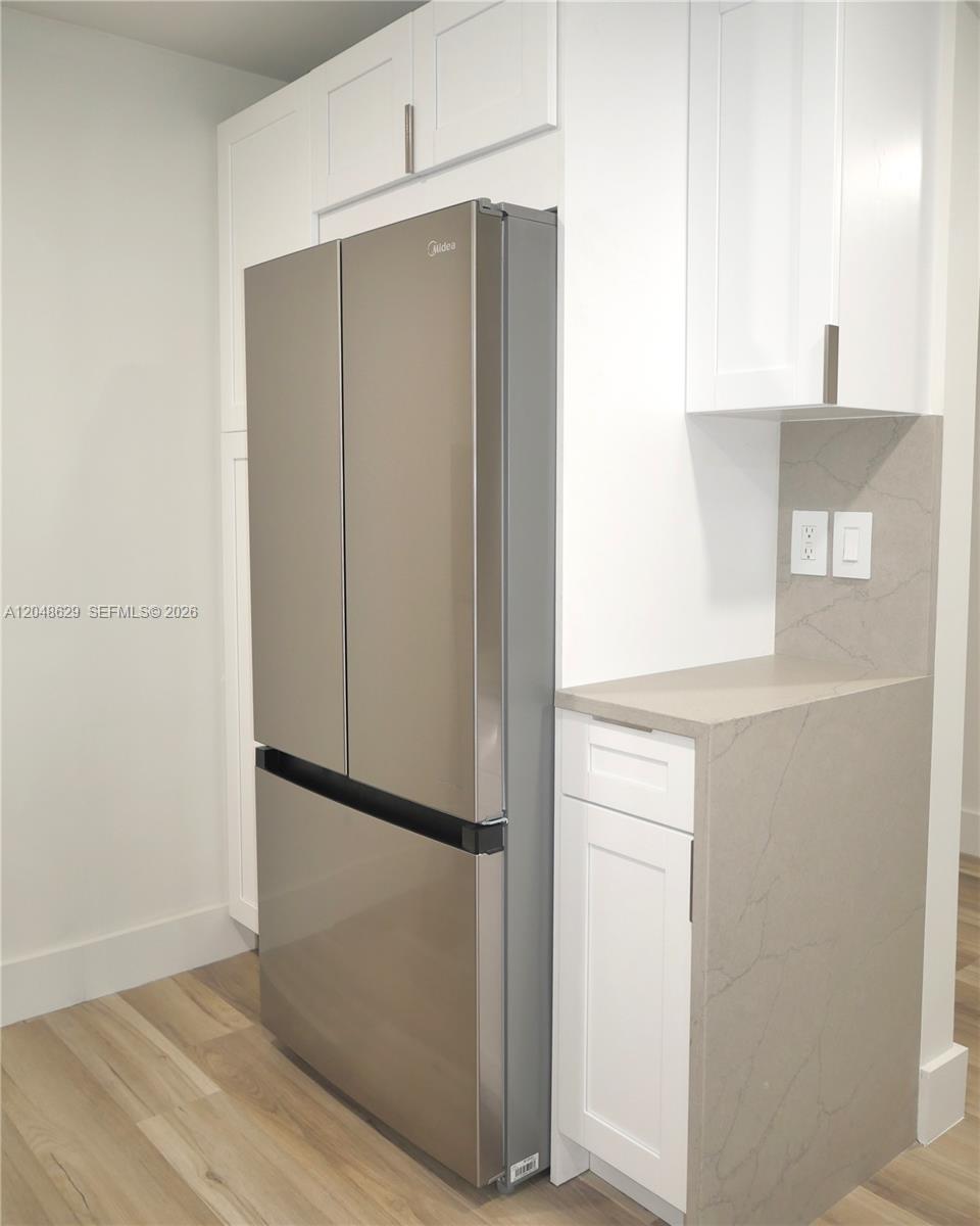 A stainless steel refrigerator is positioned next to white cabinets and a stone countertop — 3080 N Course Dr # 602, Pompano Beach FL 33069, POMPANO BEACH, FL