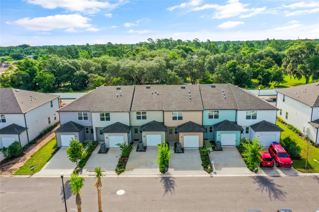 An aerial view of a row of multi-story townhouses with attached garages and driveways — 358 CADBERRY PLACE, ST CLOUD, FL