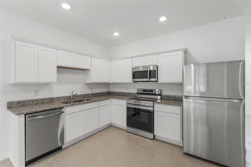 A kitchen features white cabinets, granite countertops, and stainless steel appliances — 358 CADBERRY PLACE, ST CLOUD, FL