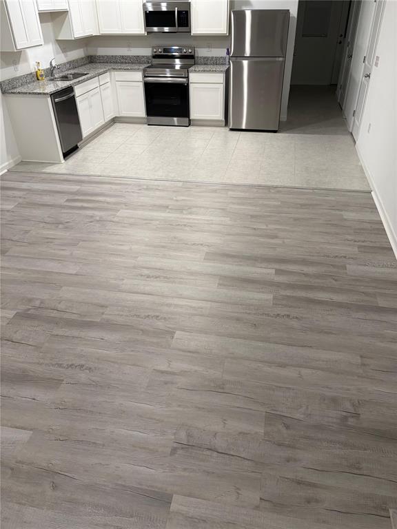 A kitchen with white cabinets, stainless steel appliances, and gray wood-look flooring — 358 CADBERRY PLACE, ST CLOUD, FL