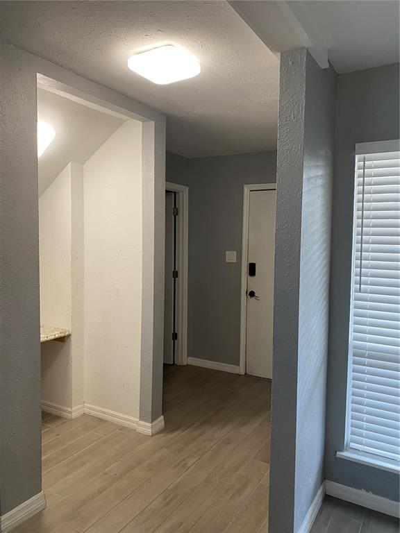 A hallway with light wood-look tile flooring, gray walls, and a small built-in desk area — 4394 SANDNER DRIVE, SARASOTA, FL