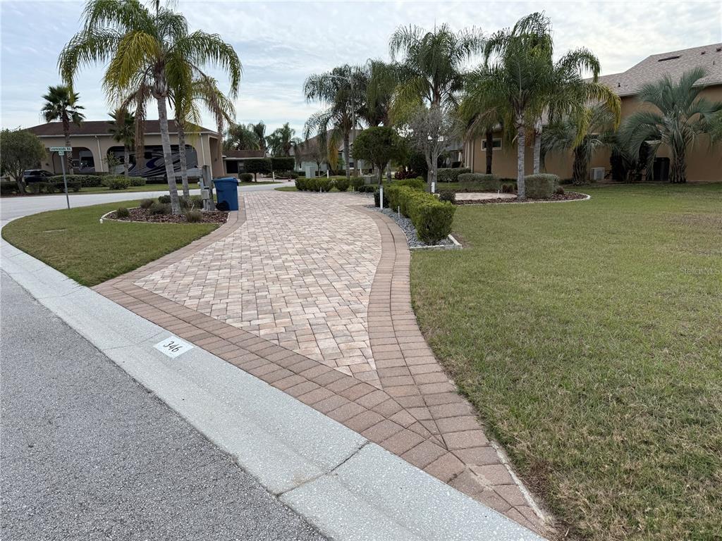 A paved driveway leads to a residential property with palm trees and manicured landscaping — 346 NOLANE LANE, POLK CITY, FL