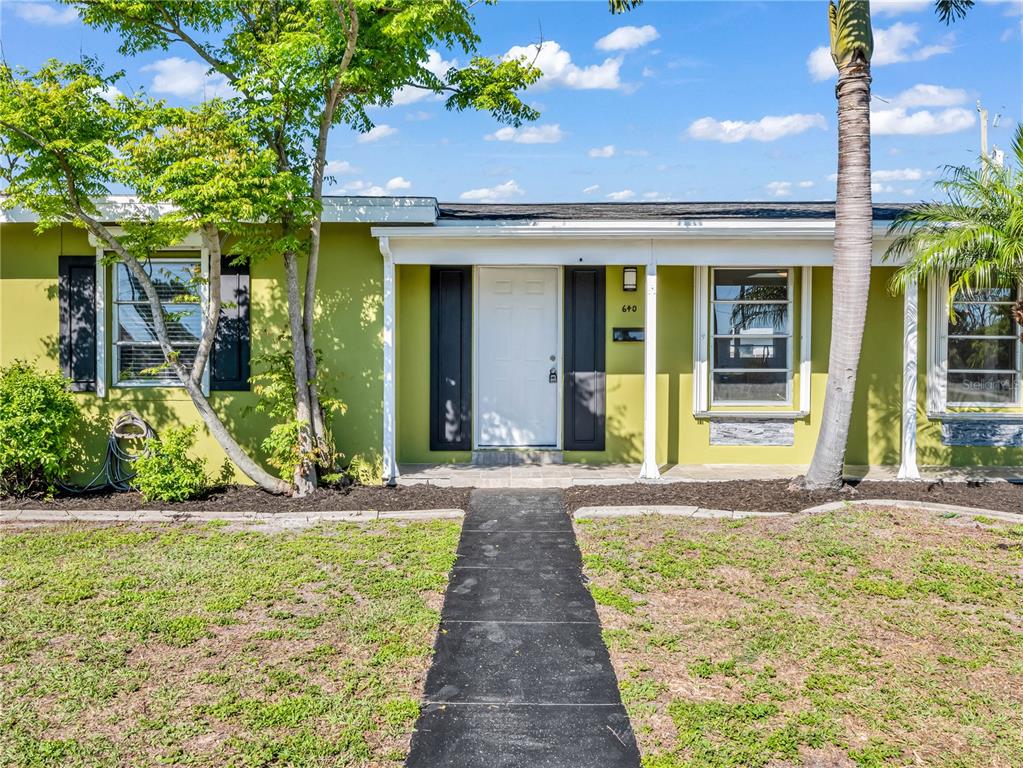 A lime green house exterior features a white front door, dark shutters, and a walkway — 640 DALTON BOULEVARD, PORT CHARLOTTE, FL