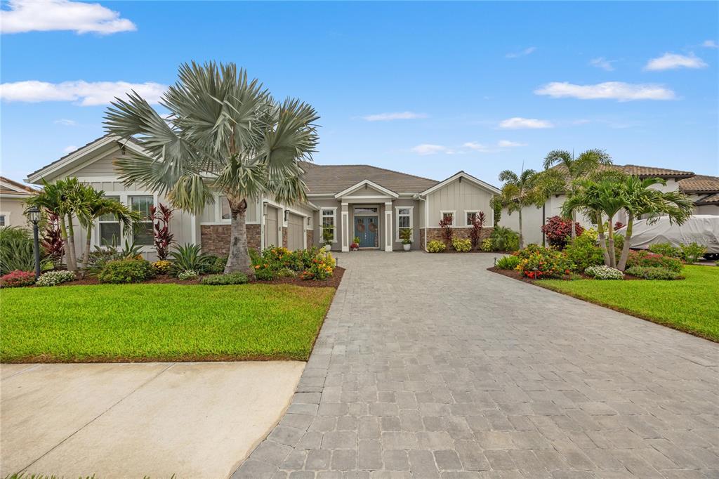 A single-story house with a stone facade, a paved driveway, and palm trees — 9479 TEQUILA SUNRISE DRIVE, SARASOTA, FL
