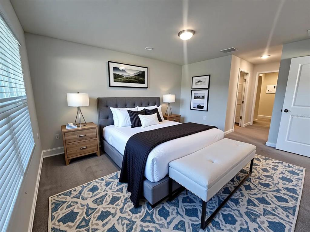 A bedroom features a gray upholstered bed, a white bench, and a blue patterned rug — 8696 SW 49TH CIRCLE, OCALA, FL
