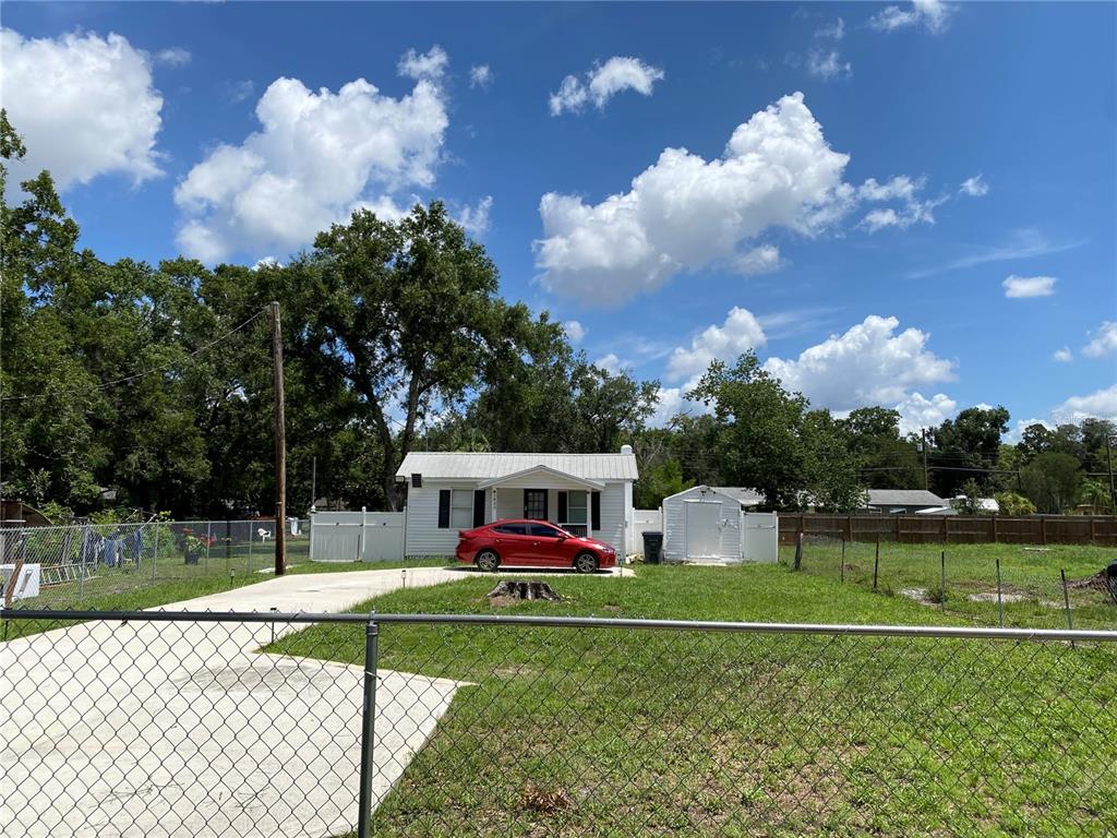 A red car is parked in the driveway of a small house with a shed — 1835 W GREENWOOD STREET, LAKELAND, FL