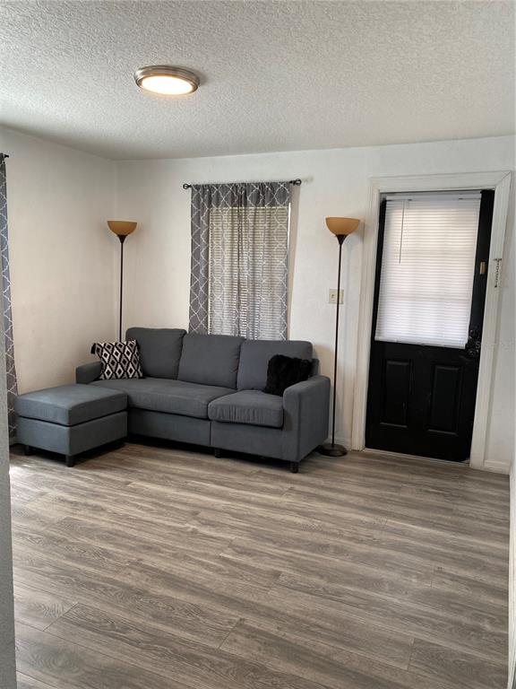 A living room features gray wood-look flooring, a gray sectional sofa, and a black door — 1835 W GREENWOOD STREET, LAKELAND, FL