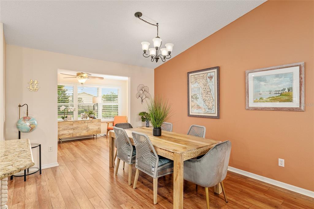 A dining room features a wooden table, grey chairs, and a map on a terracotta wall — 991 BARRYMOORE LOOP, THE VILLAGES, FL