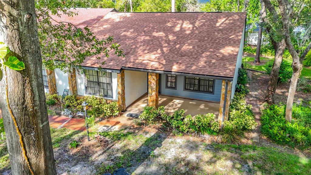 An exterior view of a house with a shingled roof, stone pillars, and a porch — 2077 WOODCUTTER COURT, SPRING HILL, FL