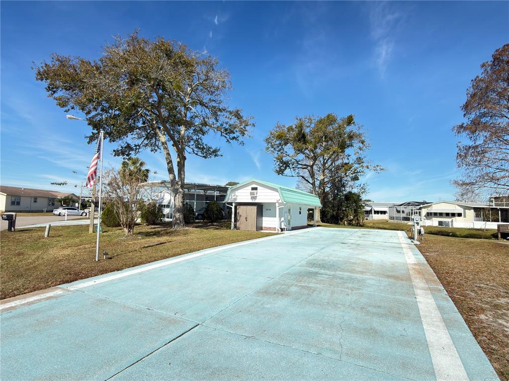 A light blue gambrel-roofed structure features a window air conditioner and an attached storage shed — 5036 SHORE LINE DRIVE, POLK CITY, FL