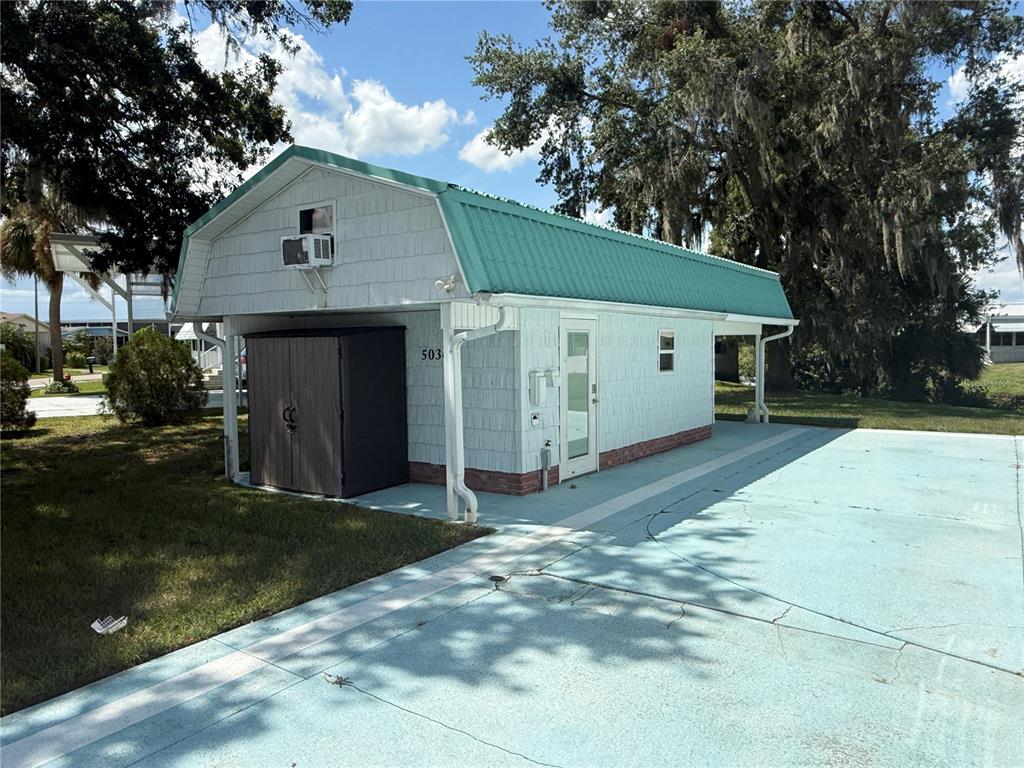 A light blue shed with a teal metal roof sits on a paved lot — 5036 SHORE LINE DRIVE, POLK CITY, FL