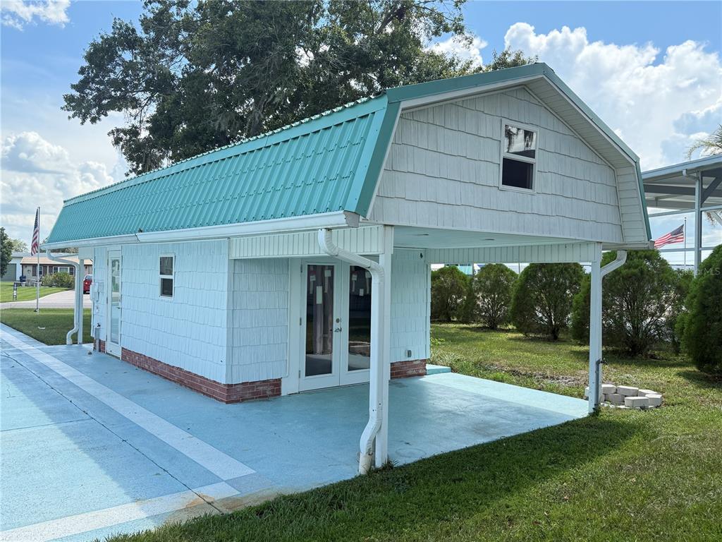 A light blue shed with a teal metal roof and an attached covered patio area — 5036 SHORE LINE DRIVE, POLK CITY, FL