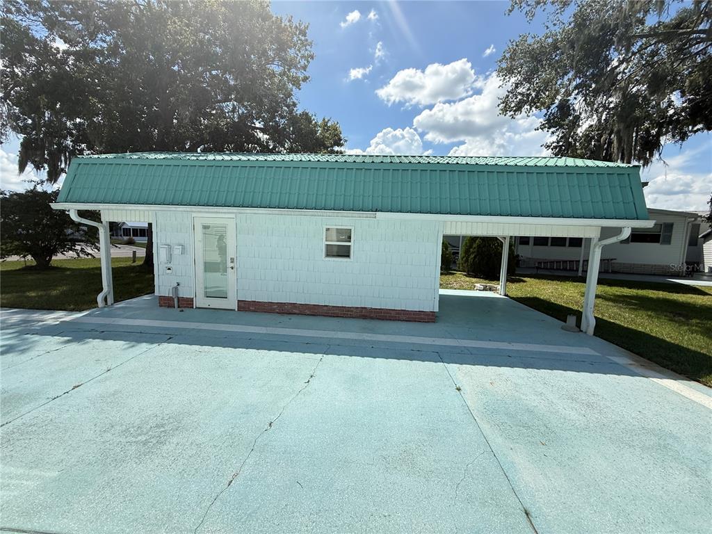 A light blue shed with a green metal roof stands on a concrete driveway — 5036 SHORE LINE DRIVE, POLK CITY, FL