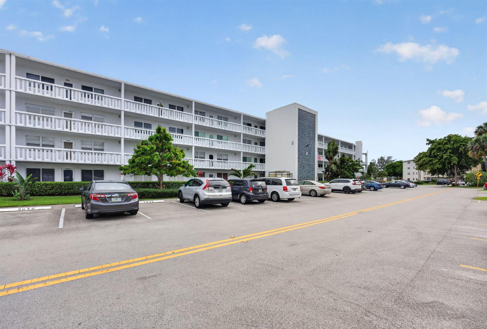 A multi-story apartment building with a parking lot in the foreground — 1025 Ventnor # H, Deerfield Beach FL 33442, DEERFIELD BEACH, FL