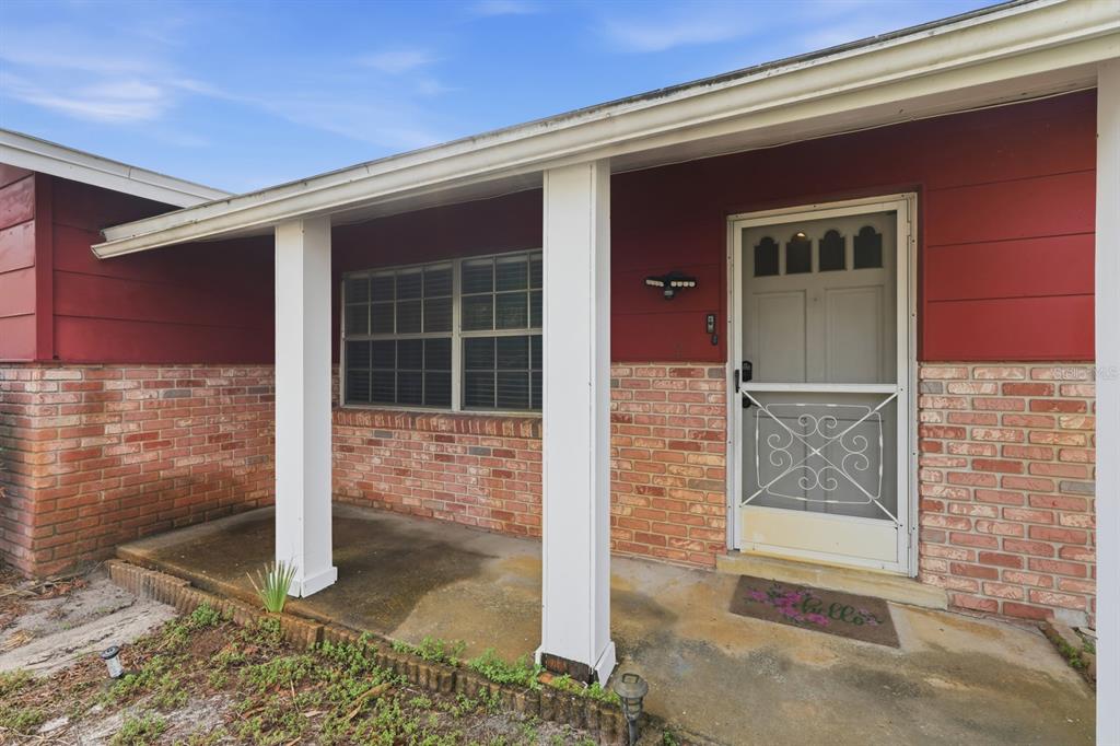 A covered porch with white columns leads to a front door with a screen door — 1317 N SHANGRI LA DRIVE, DAYTONA BEACH, FL