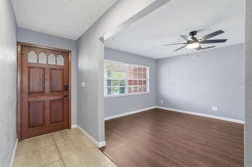 An entryway with tile flooring leads into a living room featuring wood-look laminate flooring — 1317 N SHANGRI LA DRIVE, DAYTONA BEACH, FL