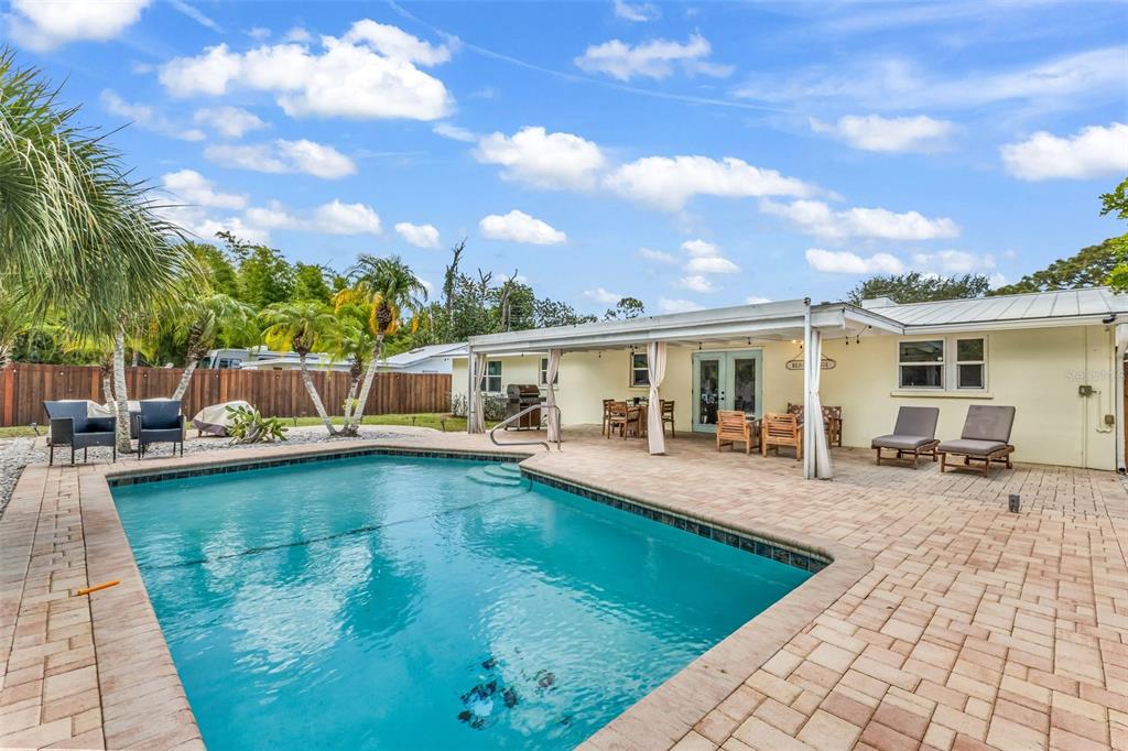 A backyard features a swimming pool, a paved patio, and a covered porch area — 1664 LAKEVIEW PLACE, ENGLEWOOD, FL