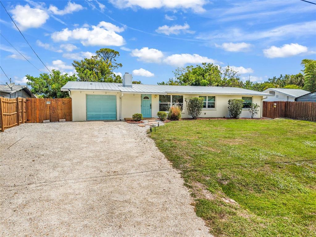 A single-story house with a light-colored exterior, a gravel driveway, and a blue garage door — 1664 LAKEVIEW PLACE, ENGLEWOOD, FL
