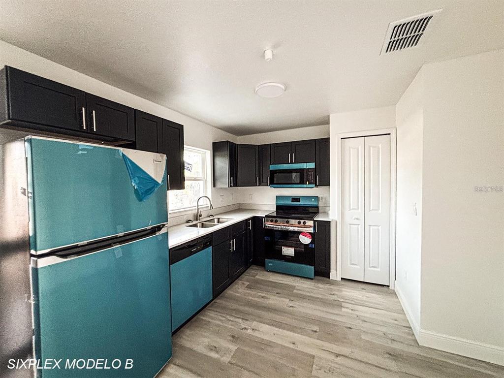 A kitchen features dark cabinets, stainless steel appliances, white countertops, and light wood-look flooring — 2201 CONWAY DRIVE UNIT 101, DELTONA, FL