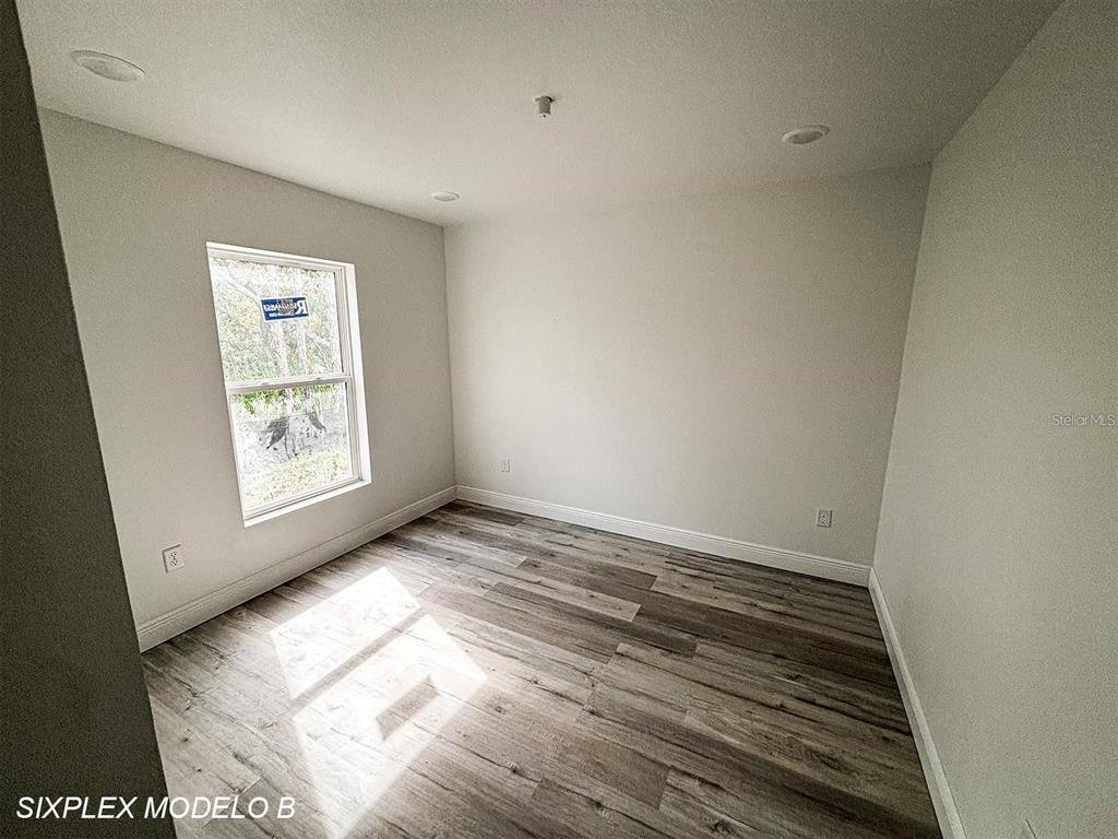 An empty bedroom features light gray walls, wood-look flooring, and a single window — 2201 CONWAY DRIVE UNIT 101, DELTONA, FL