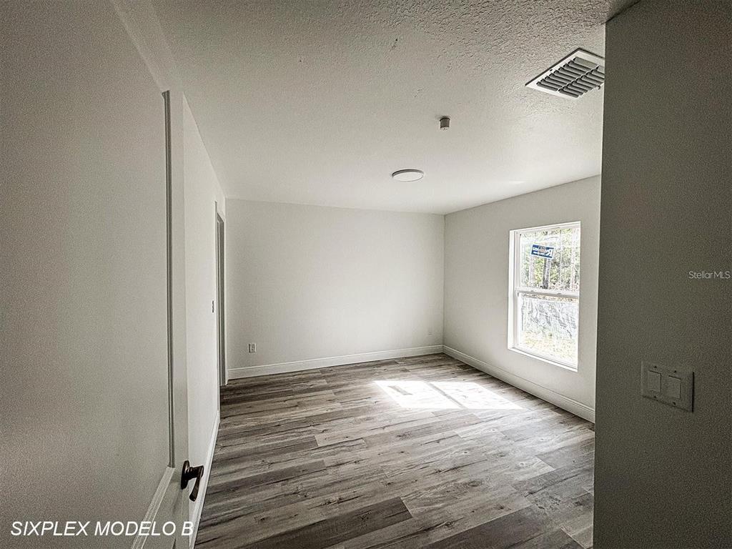 An empty room with light gray walls, wood-look flooring, and a single window — 2201 CONWAY DRIVE UNIT 101, DELTONA, FL