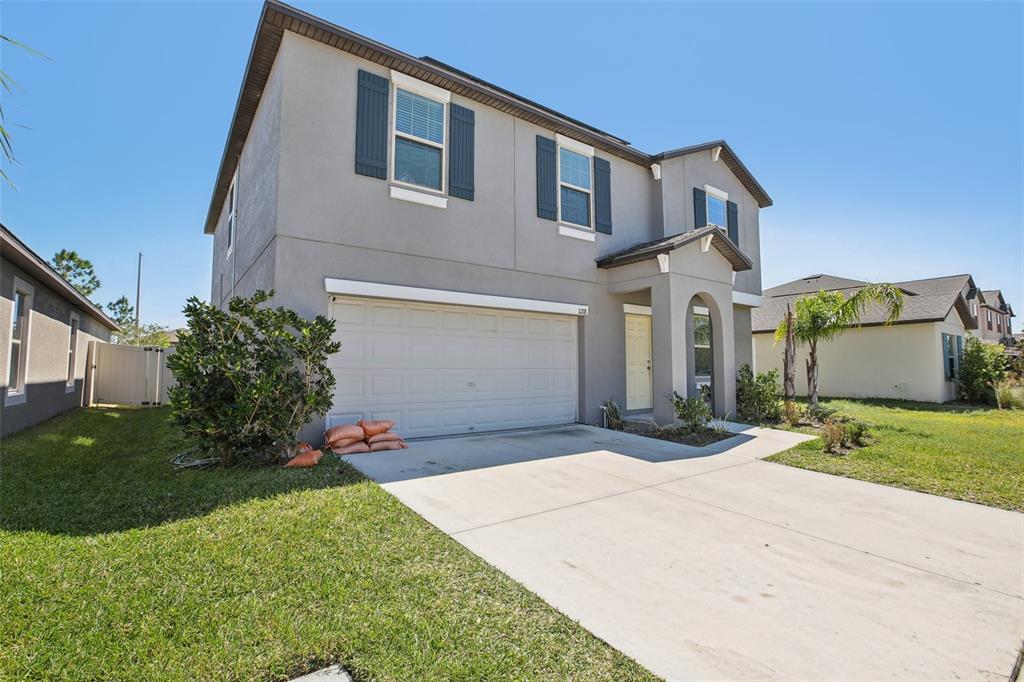 A two-story house with a gray stucco exterior, dark shutters, and a concrete driveway — 11218 SAGE CANYON DRIVE, RIVERVIEW, FL