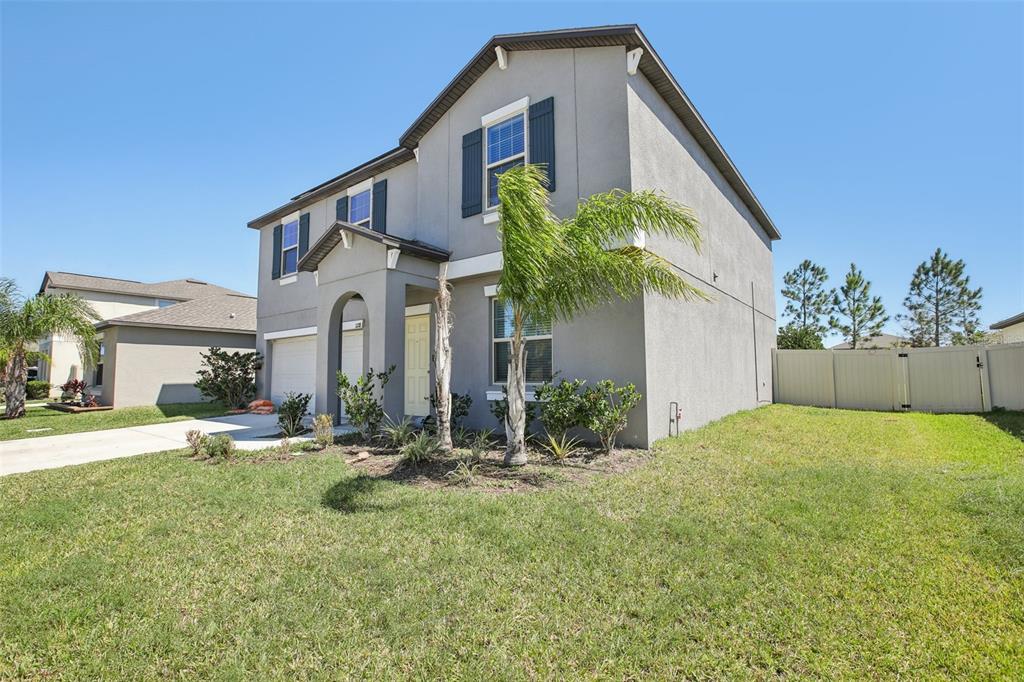A two-story gray stucco house features a front porch, a garage, and palm trees — 11218 SAGE CANYON DRIVE, RIVERVIEW, FL