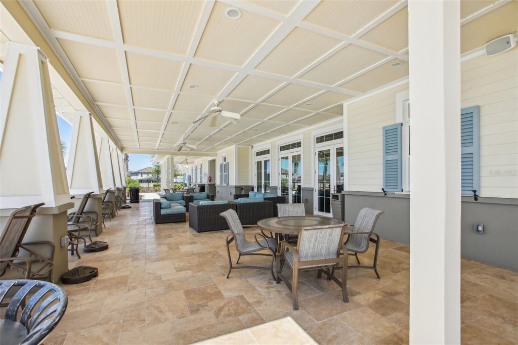 A covered outdoor patio features stone tile flooring, dining furniture, and lounge seating areas — 11218 SAGE CANYON DRIVE, RIVERVIEW, FL
