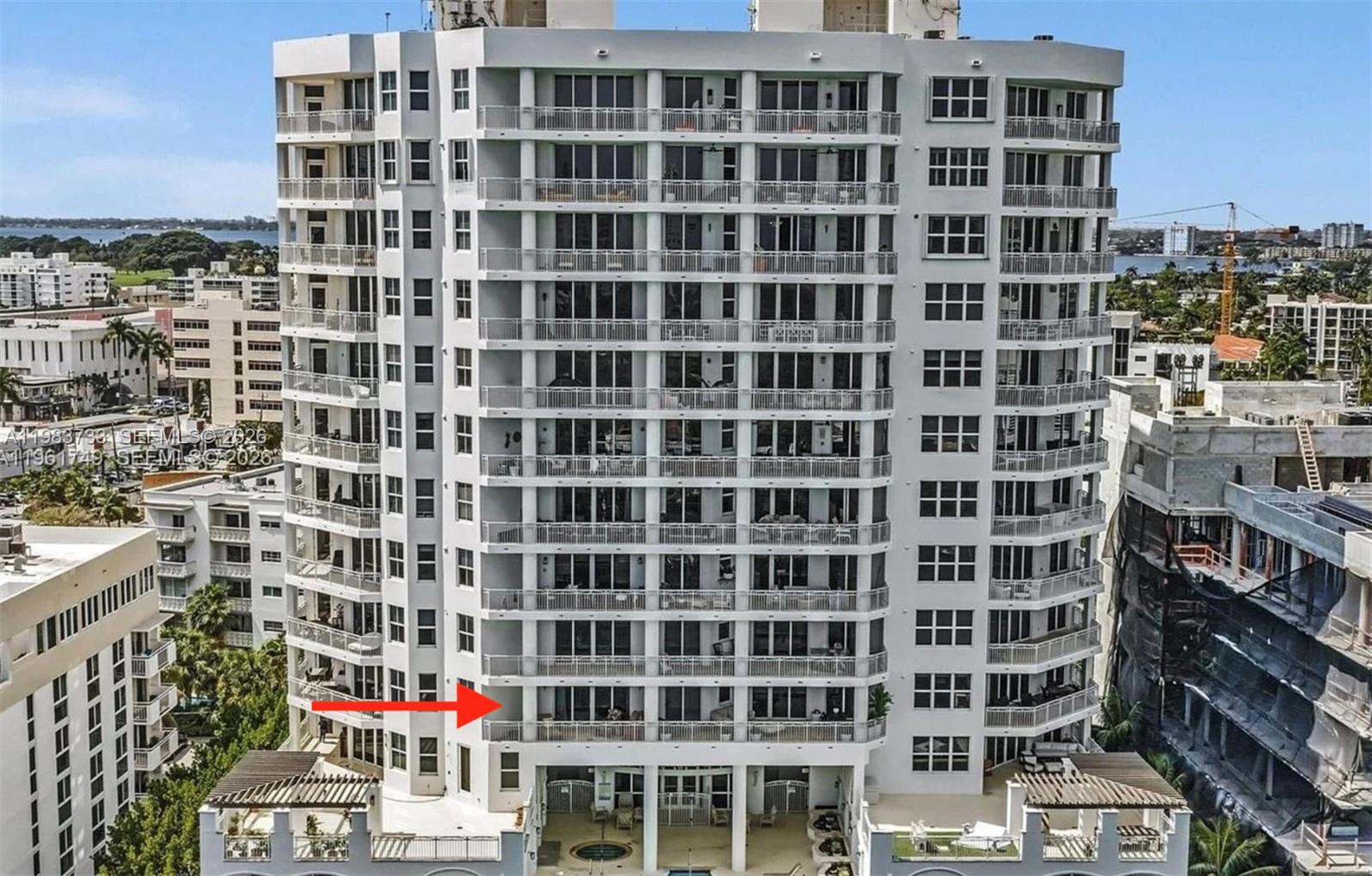 An exterior view of a multi-story white residential building with balconies and a red arrow — 9751 E Bay Harbor Dr # 6C, Bay Harbor Islands FL 33154, BAY HARBOR ISLANDS, FL