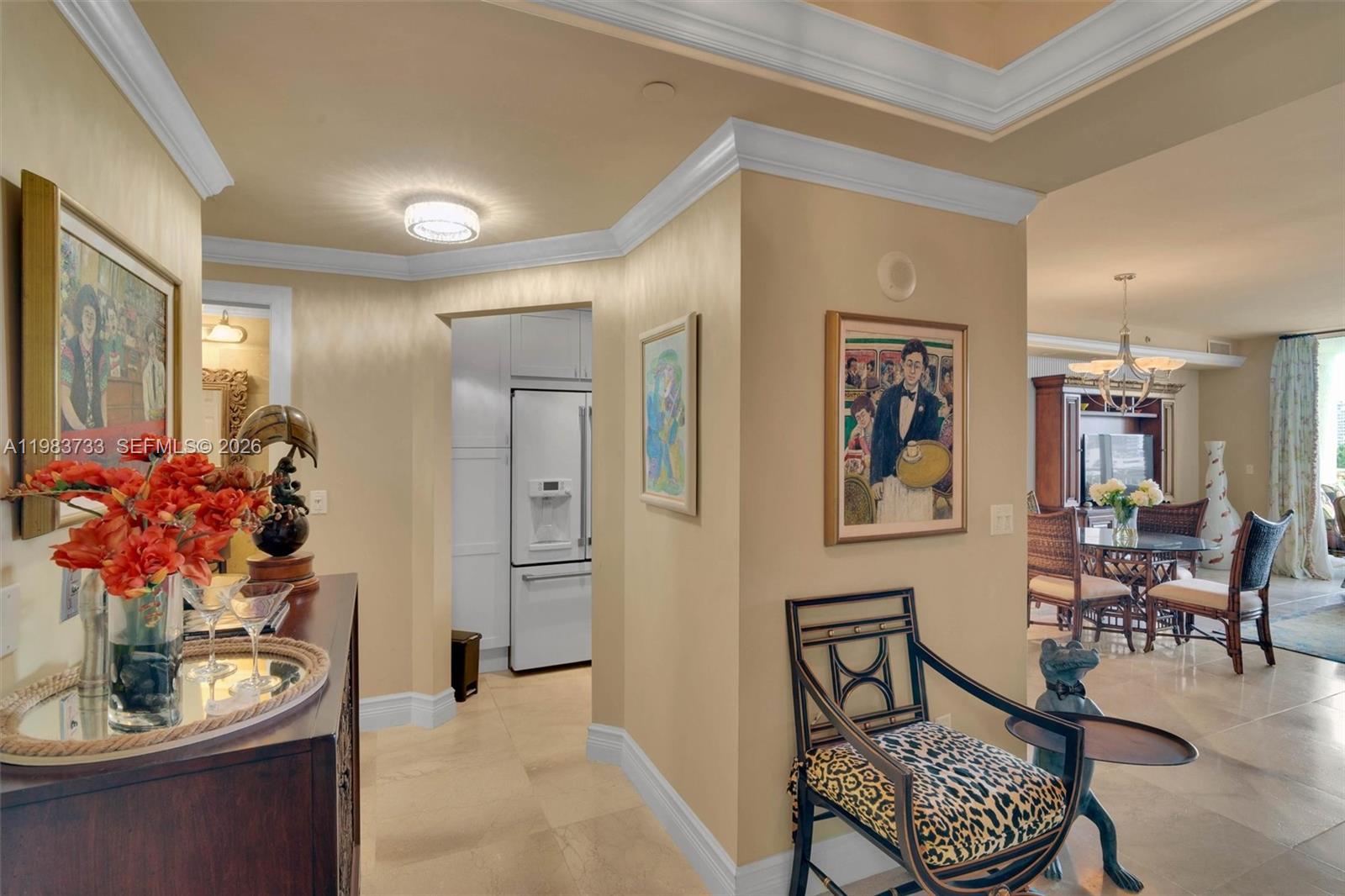 A hallway with beige walls, crown molding, and tile flooring leads toward a kitchen area — 9751 E Bay Harbor Dr # 6C, Bay Harbor Islands FL 33154, BAY HARBOR ISLANDS, FL