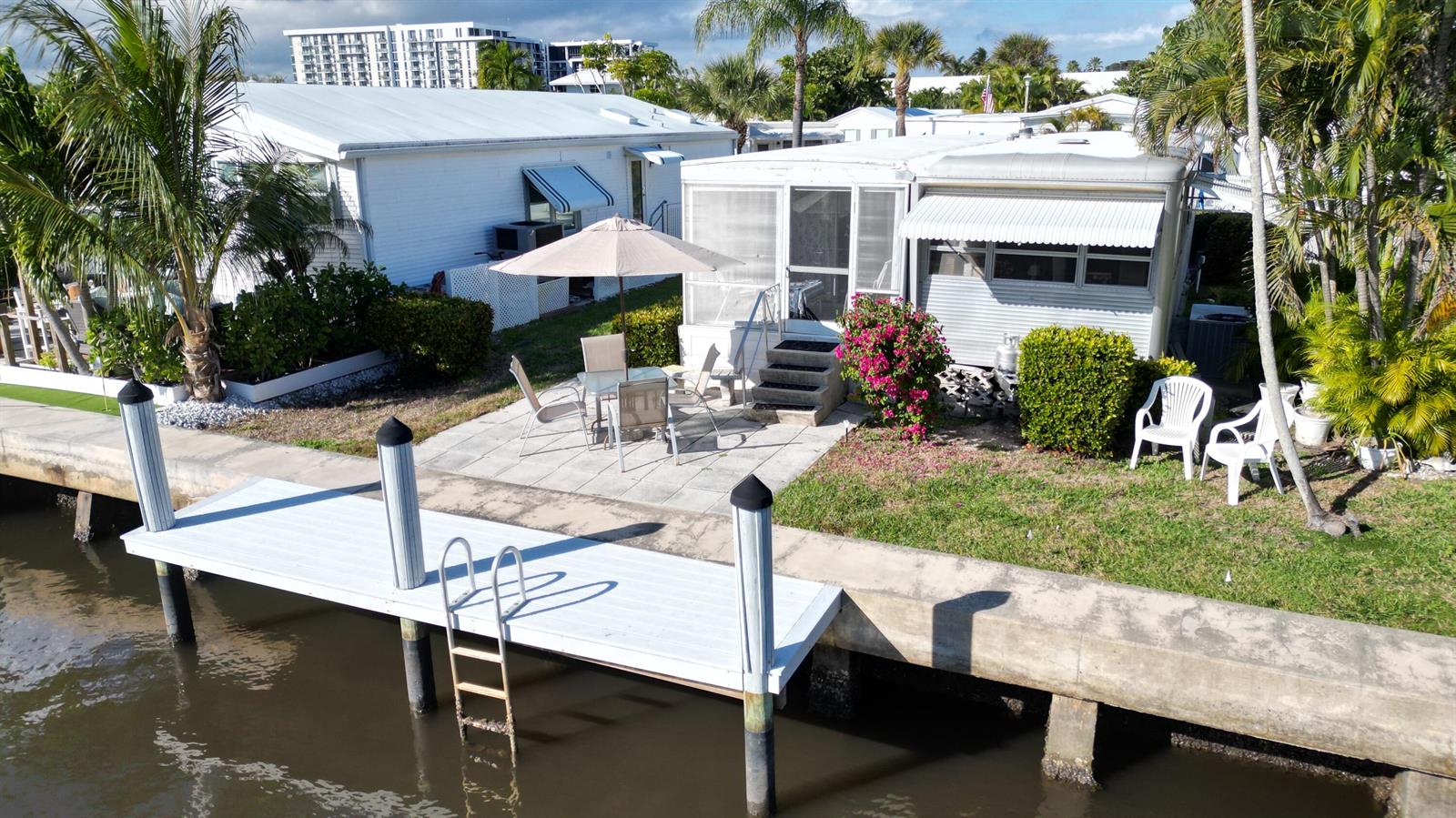 An aerial view of a waterfront mobile home with a patio, dock, and palm trees — 203 S Ibis Drive # R, Briny Breezes FL 33435, BRINY BREEZES, FL