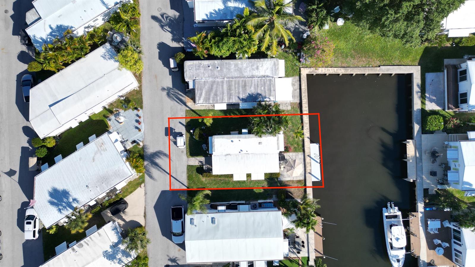 An aerial view shows a single-story home with a white roof situated along a canal — 203 S Ibis Drive # R, Briny Breezes FL 33435, BRINY BREEZES, FL