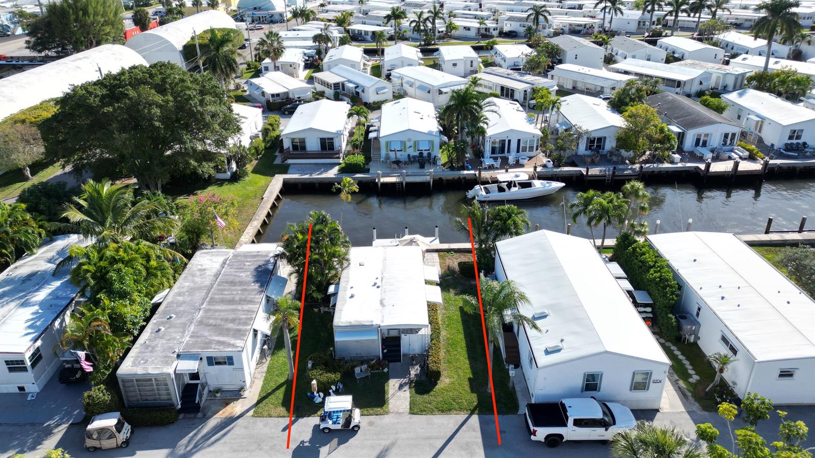 An aerial view shows a waterfront mobile home with a private dock and boat — 203 S Ibis Drive # R, Briny Breezes FL 33435, BRINY BREEZES, FL
