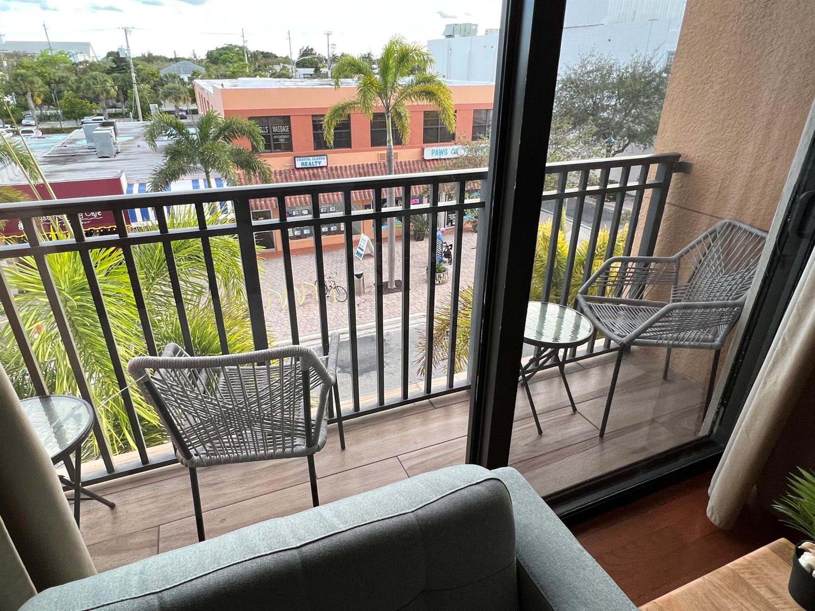 A balcony with two chairs and small tables overlooks a street with palm trees — 511 Lucerne Avenue # 316, FL 33460, FL