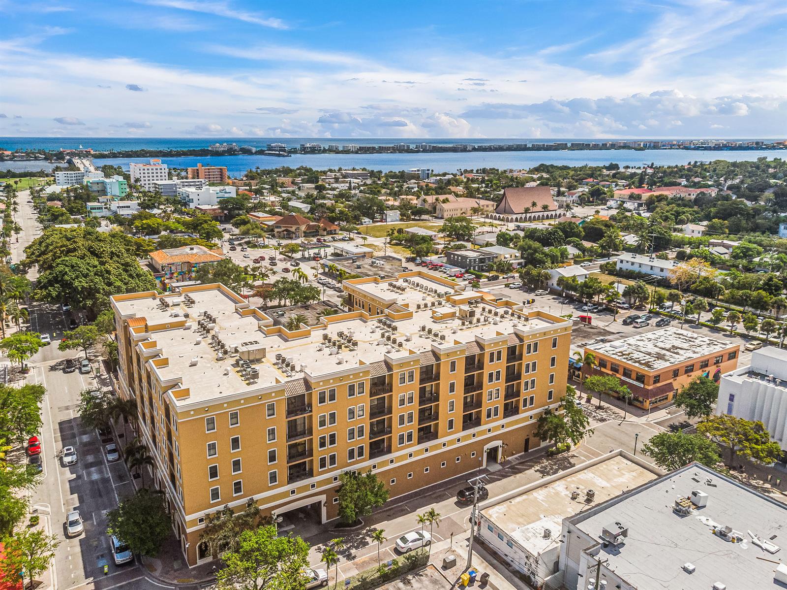 An aerial view shows a large, multi-story yellow apartment building in a coastal city — 511 Lucerne Avenue # 316, FL 33460, FL