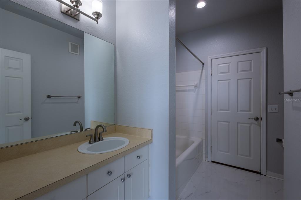A bathroom features a vanity with a beige countertop, a mirror, and a tub-shower combination — 18001 RICHMOND PLACE DRIVE UNIT 427, TAMPA, FL