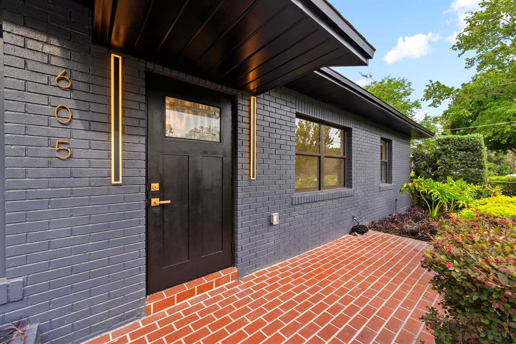 A dark gray brick house exterior features a black front door and red brick patio — 605 N WOODLYNNE AVENUE, TAMPA, FL
